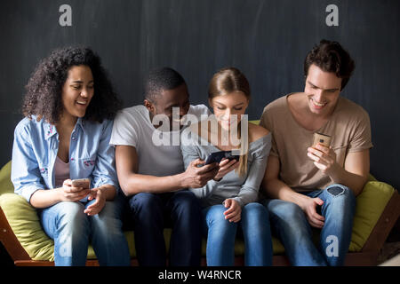 Smiling divers amis discutent de nouvelles apps pour téléphone mobile. Banque D'Images