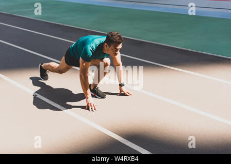 Mixed Race sportsman sur la position de démarrage à stade Banque D'Images