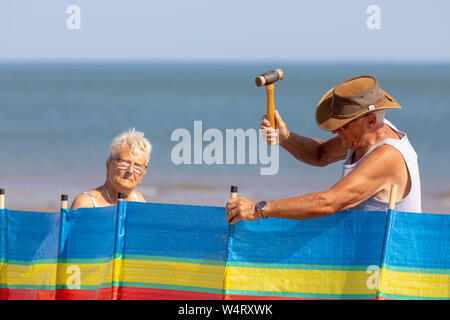 En martelant quelques enjeux pour un coupe-vent et coupe-ombre sur plage de Colwyn Bay, au nord du Pays de Galles au cours météo canicule dans la région de Wales Banque D'Images