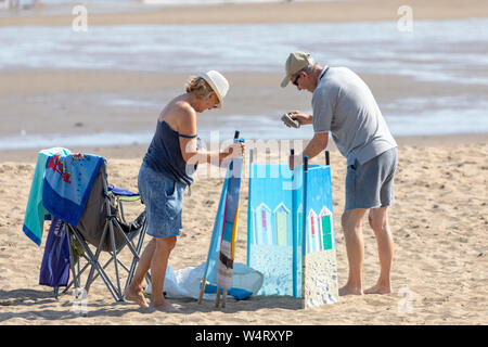 En martelant quelques enjeux pour un coupe-vent et coupe-ombre sur plage de Colwyn Bay, au nord du Pays de Galles au cours météo canicule dans la région de Wales Banque D'Images