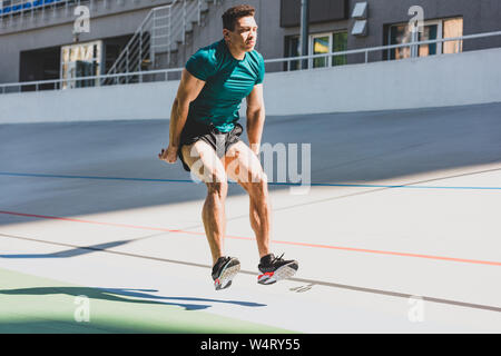 Mixed Race sportsman faisant le saut en longueur à stade en plein soleil Banque D'Images