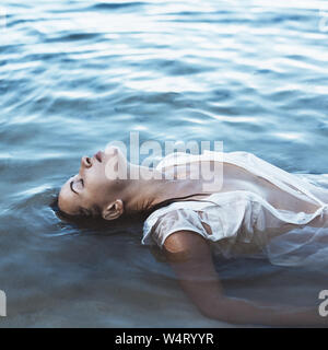 Femme allongée sur le dos dans la mer, Seychelles Banque D'Images