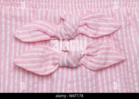 Sur Bow robe. Close-up détails de décoration deux des cravates à rayures blanc rose robe d'été de petite fille. Macro. Banque D'Images