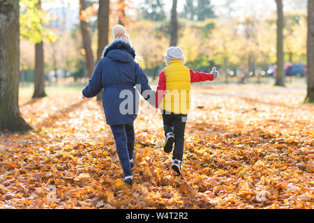 Des enfants heureux tournant au autumn park Banque D'Images