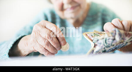 Photo gros plan détaillé de womans mains âgées méconnaissable restants de comptage de pièces dans son portefeuille de retraite après le paiement des factures. Banque D'Images