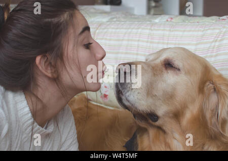 Teenage girl kissing her golden retriever dog Banque D'Images