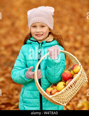 Fille avec des pommes dans panier en osier à autumn park Banque D'Images