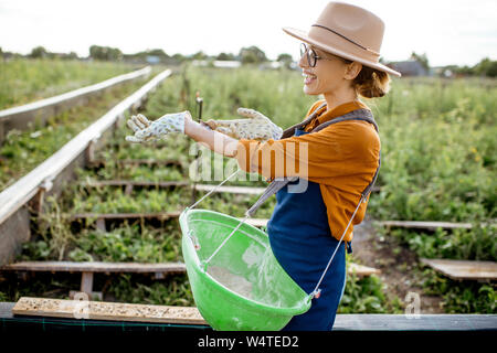 Portrait of a young woman farmer avec escargot sur la main, debout sur les terres agricoles pour la culture des escargots en plein air Banque D'Images