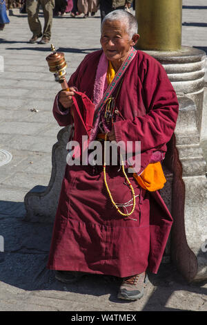 La Chine, Tibet, Lhasa, une nonne bouddhiste Tibétain avec son moulin à prières prend un repos tout en circumambulating le Palais du Potala. Banque D'Images