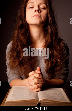 Jeune femme qui prie sur la sainte bible avec rosaire Banque D'Images