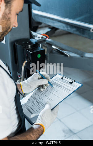Portrait de auto mechanic holding clipboard lors de l'écriture au service de voiture Banque D'Images