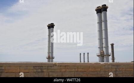 Les cheminées d'usine contre ciel nuageux au-dessus du mur de briques. Banque D'Images