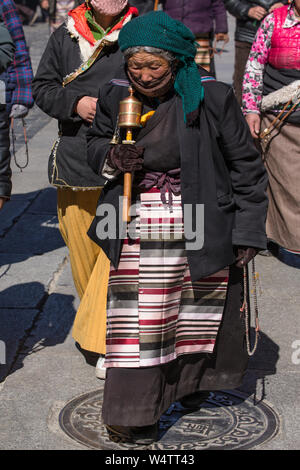 La Chine, Tibet, Lhasa, une vieille femme circumambulates pèlerin tibétain le Temple de Jokhang, avec son chapelet mala aussi porter son pangden bangdian colorés traditionnels ou tablier. Banque D'Images