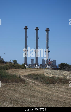 Voie menant à l'usine avec cheminées contre le ciel bleu en paysage méditerranéen. Banque D'Images