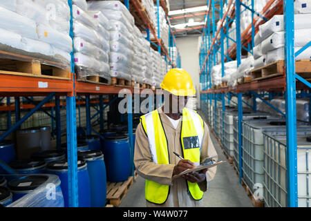 Travailleur homme writing on clipboard in warehouse Banque D'Images