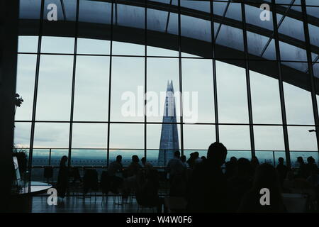 Le gratte-ciel d'échardes dans les couleurs gris et bleu à Londres, Royaume-Uni shot from the Sky Garden restaurant. Le premier plan de la photo est d'une foule de personnes. Banque D'Images