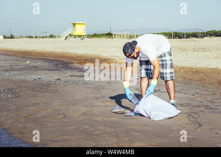 L'homme la collecte de matières plastiques qui polluent l'océan dans un sac en plastique, des gens qui aident à conserver la nature propre et ramasser les déchets de plage, camp de bénévoles Banque D'Images