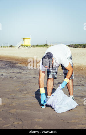 L'homme la collecte des déchets qui polluent l'océan dans un sac en plastique, des gens qui aident à conserver la nature propre et ramasser les matières plastiques à partir de la plage, camp de bénévoles Banque D'Images