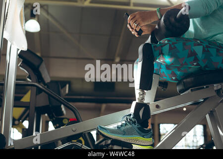 Mobilité active senior woman using mobile phone tout en exerçant in fitness studio Banque D'Images