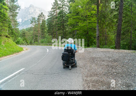 Personne handicapée dans un fauteuil roulant électrique de circuler sur la rue, un chemin Banque D'Images