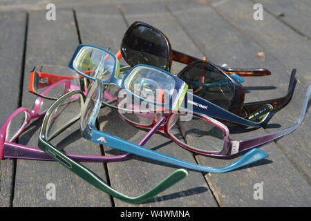 Grand nombre de pans de verres de lunettes dépliée disposés dans un motif abstrait aléatoire sur une surface à lattes en plein soleil Banque D'Images