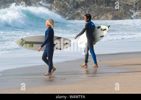 Deux jeunes hommes surfers carrying surfboard leur baguette à pied de la mer à de Fistral Newquay en Cornouailles. Banque D'Images