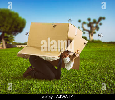 L'homme se défend de l'attaque des moustiques se cachant dans une boite en carton Banque D'Images