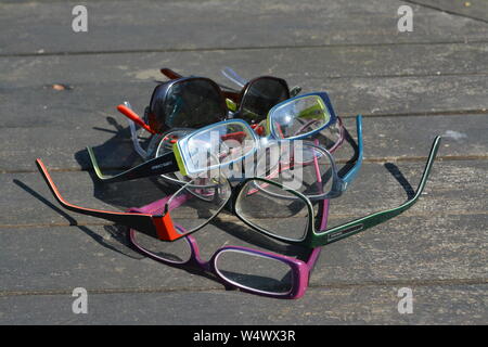 Grand nombre de pans de verres de lunettes dépliée disposés dans un motif abstrait aléatoire sur une surface à lattes en plein soleil Banque D'Images