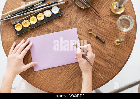 Un rédacteur écrit une histoire. Une main est la tenue d'un stylo encre en face d'une feuille vierge. Espace libre pour le texte. Soft focus Banque D'Images