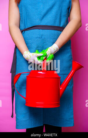 La photo d'une femme avec un tablier rouge bidon à vide sur fond bleu en studio Banque D'Images