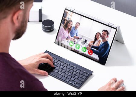 Businessman la visioconférence avec ses collègues sur l'Hybride Laptop On Desk In Office Banque D'Images