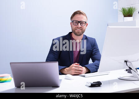 Portrait d'un jeune homme assis en face de l'ordinateur sur le lieu de travail Banque D'Images