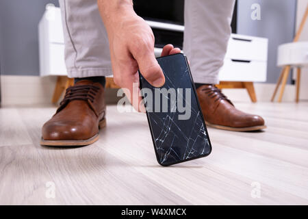 La main de l'homme prendre le téléphone mobile à écran cassé Banque D'Images