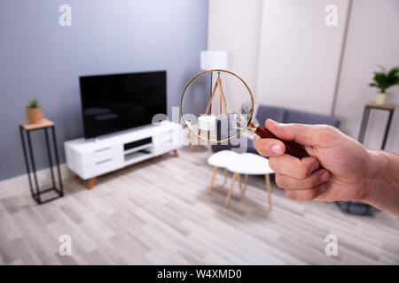 Close-up of Man's Hand Holding Magnifying Glass Recherche dans la salle de séjour Banque D'Images