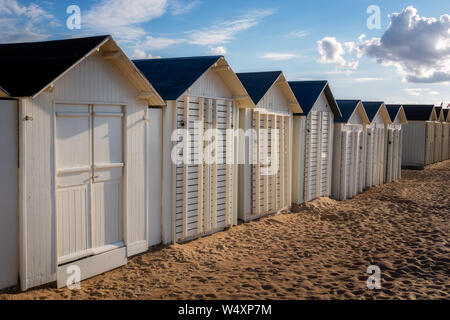 Rangée de cabines de plage en bois blanc ou cabines à côté de la plage de Riva Bella sur début de soirée, Ouistreham, Normandie, France. Banque D'Images