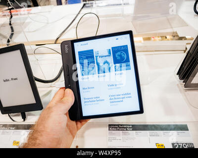 Paris, France - Jul 25, 2019 : man main tenant la lecture de l'eReader Kobo Forma est un e-reader produites par l'entreprise torontoise Kobo Inc en français supermarché électronique FNAC Banque D'Images