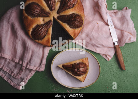 Tarte aux poires sur un essuie-tout sur une table verte. Voir ci-dessus avec un gâteau fait avec des poires entières. Banque D'Images