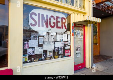 Façade de machine à coudre Singer à Solano Avenue à Berkeley, Californie, avec une signalisation en vitrine éclectique, y compris signer prétendant être plus ancien concessionnaire Singer, le 18 décembre 2018. () Banque D'Images