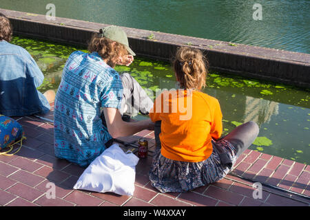 Les jeunes se rafraîchir et se relaxer à l'extérieur du centre d'exposition et de Barbican concert hall lors d'un jour très chaud à Londres, Royaume-Uni Banque D'Images