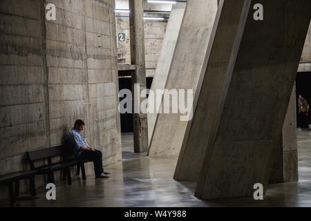 Homme assis sur un banc à lui seul au téléphone - Tate Modern - Londres - Juillet 2019 Banque D'Images