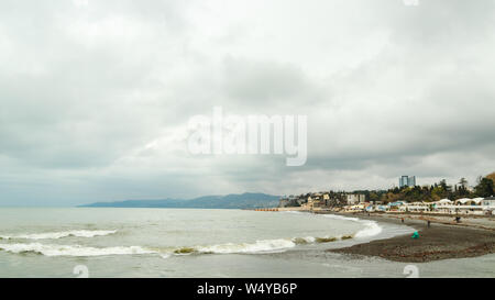 Les gens à l'eau-méconnaissable avant avant tempête. Des bouffées d'eau de mer. Vagues à proximité de la mer. Ciel nuageux sombre au-dessus de la mer. L'eau pulvérisée sur la rive. H gris Banque D'Images