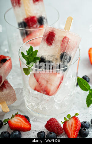 Sucettes glacées au champagne avec des fraises, framboises et bleuets Banque D'Images