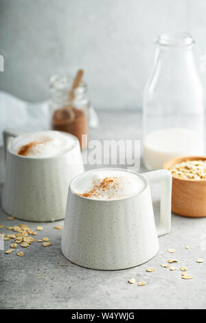 Le lait d'avoine en mousse épaisse avec latte tasses en céramique garnie de cannelle Banque D'Images