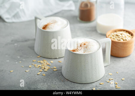 Le lait d'avoine en mousse épaisse avec latte tasses en céramique garnie de cannelle Banque D'Images