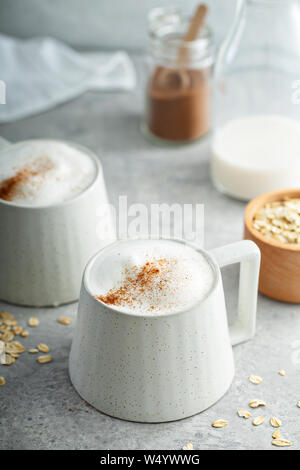 Le lait d'avoine en mousse épaisse avec latte tasses en céramique garnie de cannelle Banque D'Images