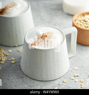 Le lait d'avoine en mousse épaisse avec latte tasses en céramique garnie de cannelle Banque D'Images