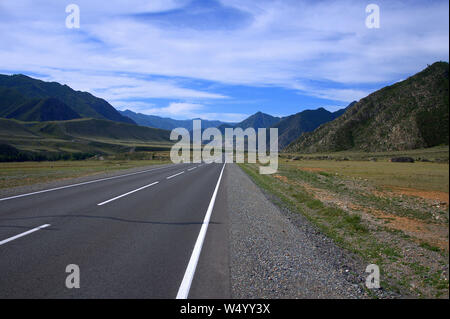 Route asphaltée traverse une vallée verte prise en sandwich entre les montagnes. L'Altaï, Sibérie, Russie. Banque D'Images