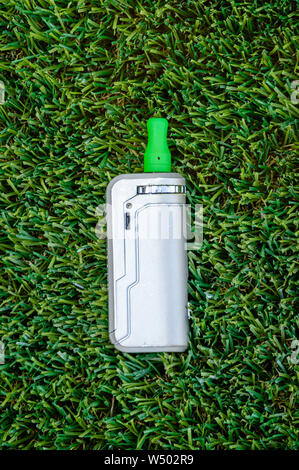 Vape isolés stylo avec le THC CBD jus huile vape cartouche sur une fond d'herbe verte. Banque D'Images