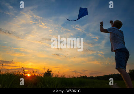 Un jeune homme lance un cerf-volant dans le ciel. Silhouette contre le coucher du soleil. Le concept de liberté, de loisirs d'été, animation dans la nature. Le minimalisme, Banque D'Images