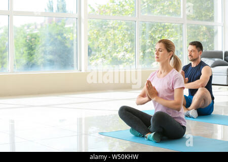 Couple heureux en amour faisant du yoga à la maison Banque D'Images